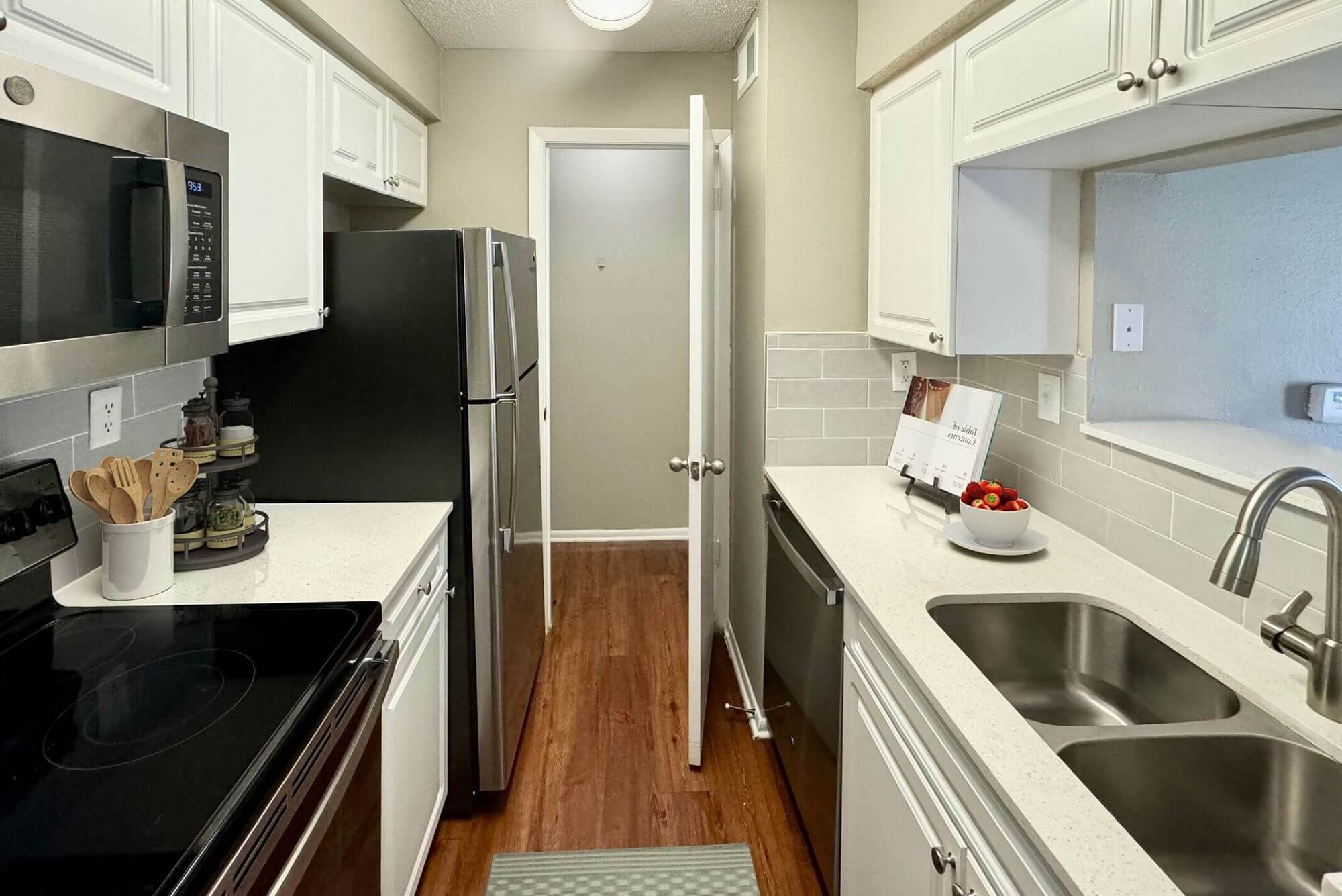 kitchen with wood-style flooring, designer lighting, stainless steel appliances, and dual sink.