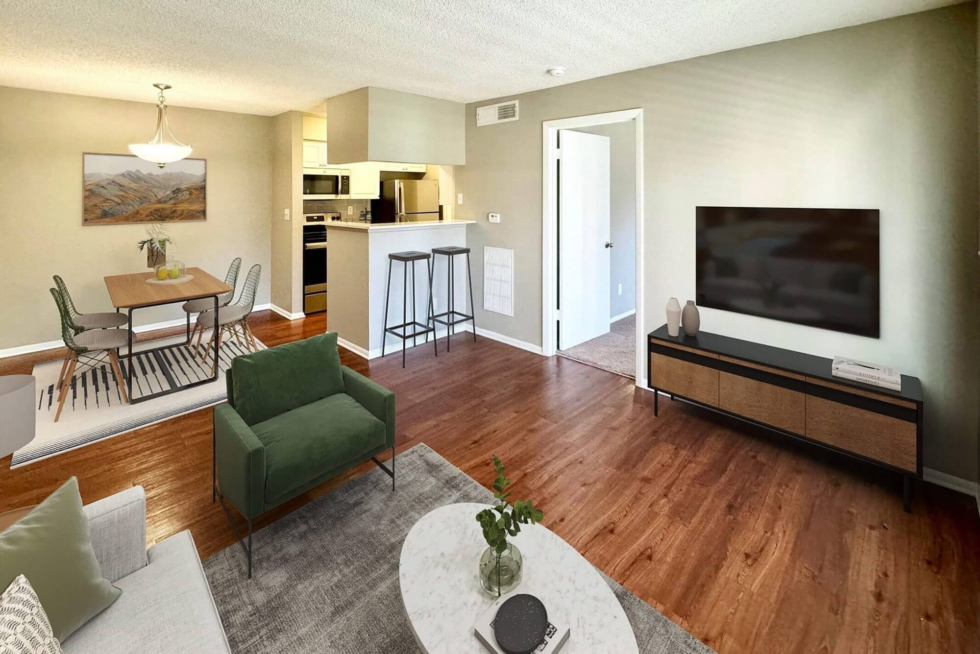 living room with wood-style flooring, mounted television, open access to the dining room, and couch seating.