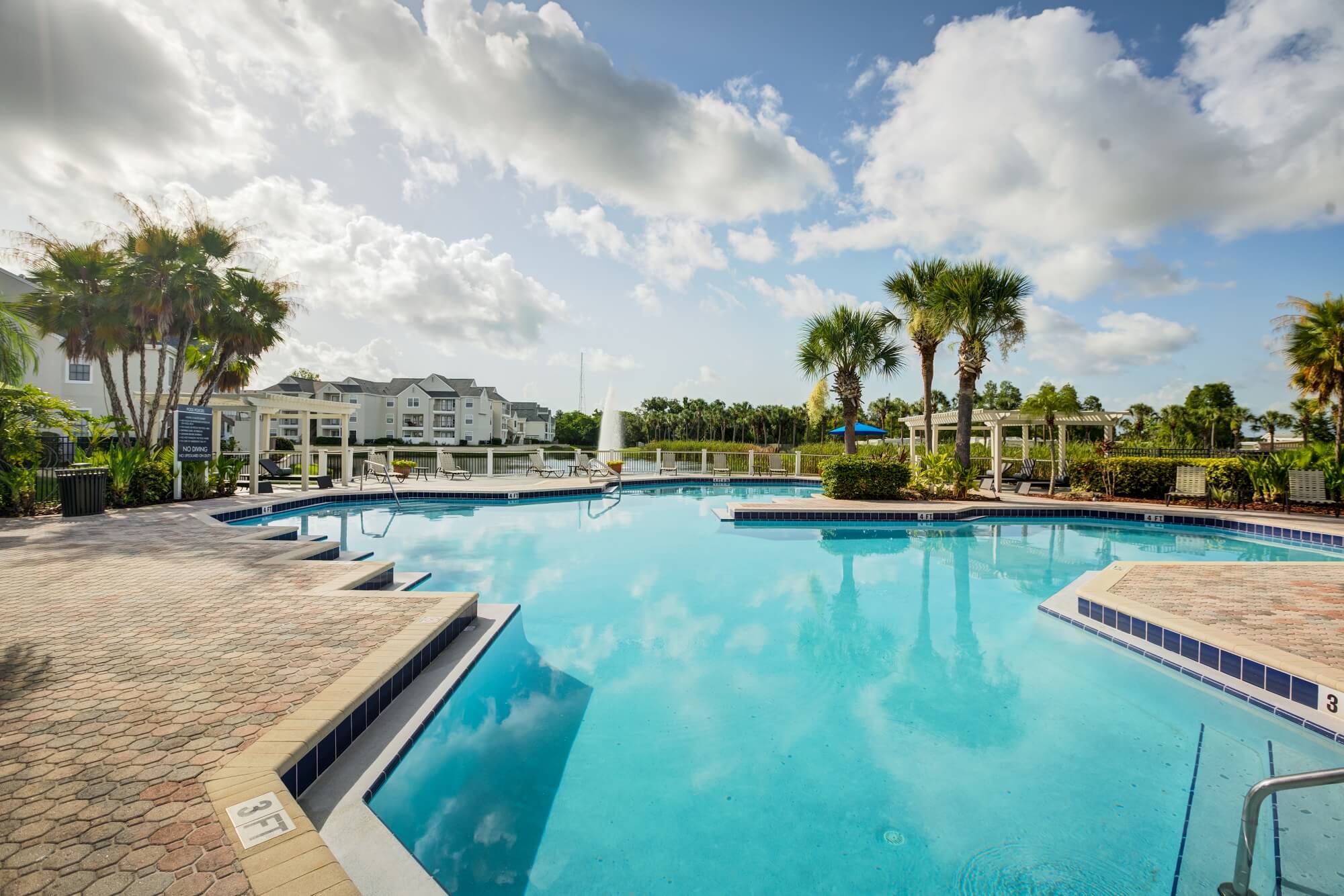 large pool with lounge chairs and view of fountain.