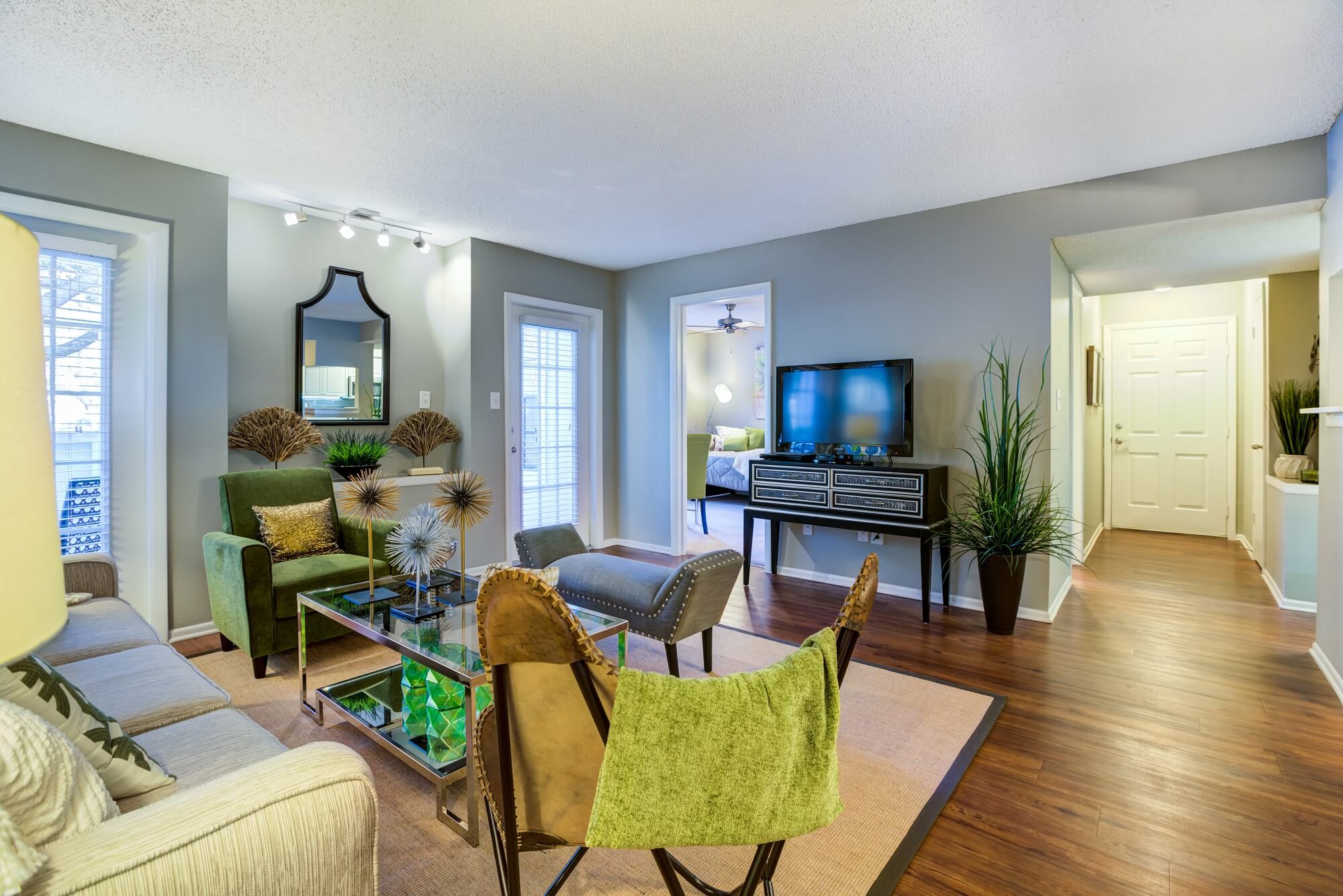 living area with wood floors, decor, and view of bedroom and front door.