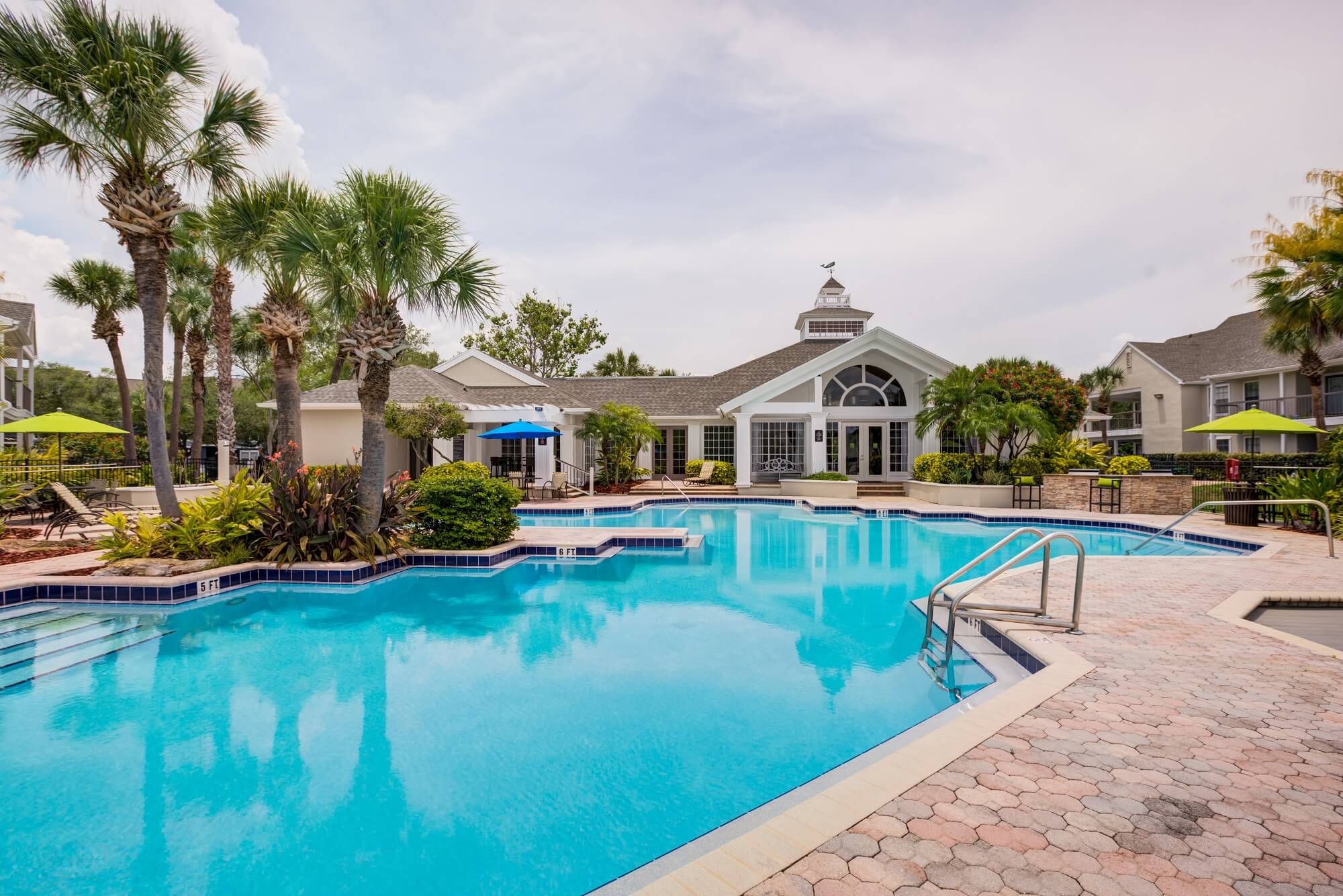 large pool view with palm trees and view of the clubhouse.