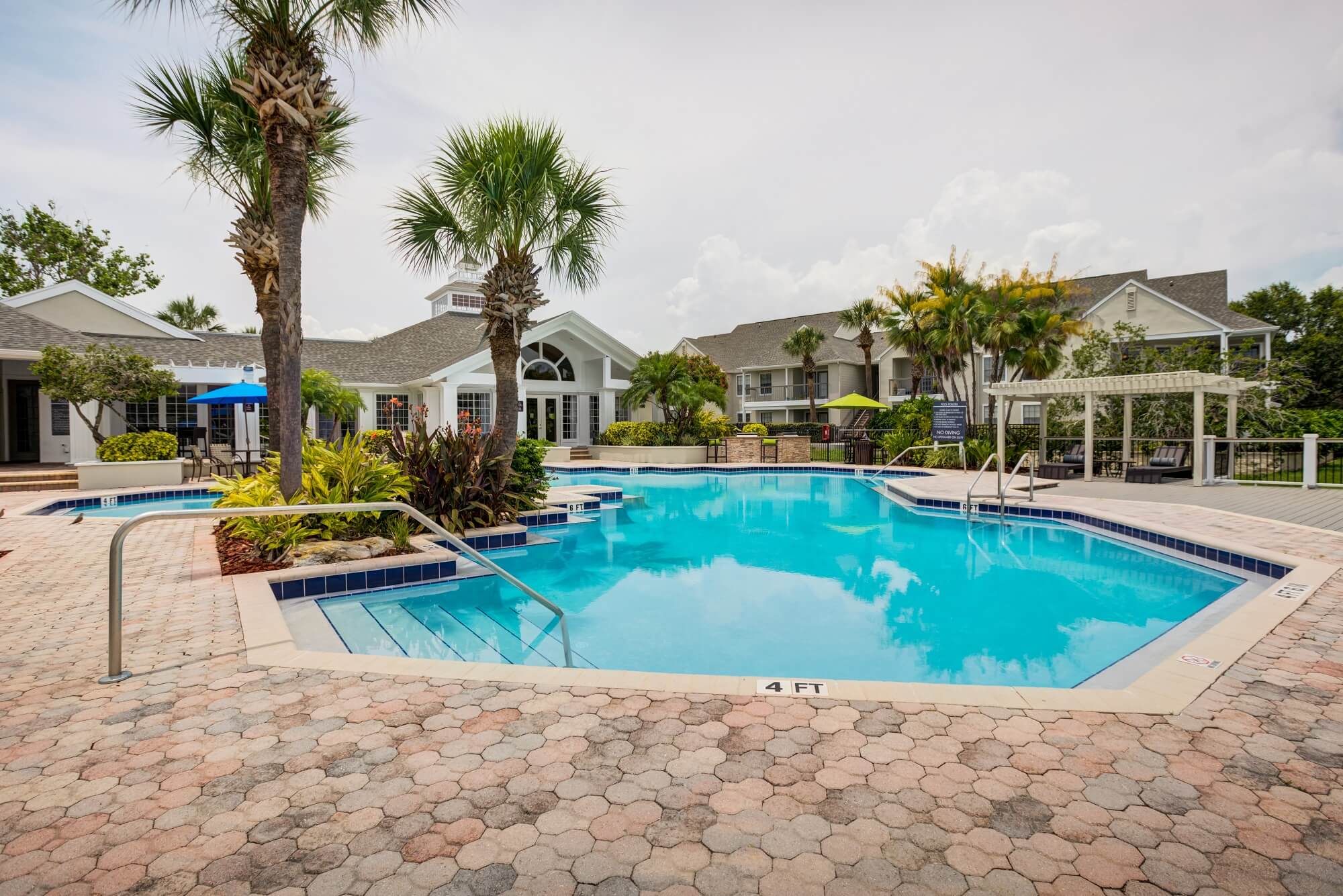 pool view with palm trees, shaded lounge area, and clubhouse.