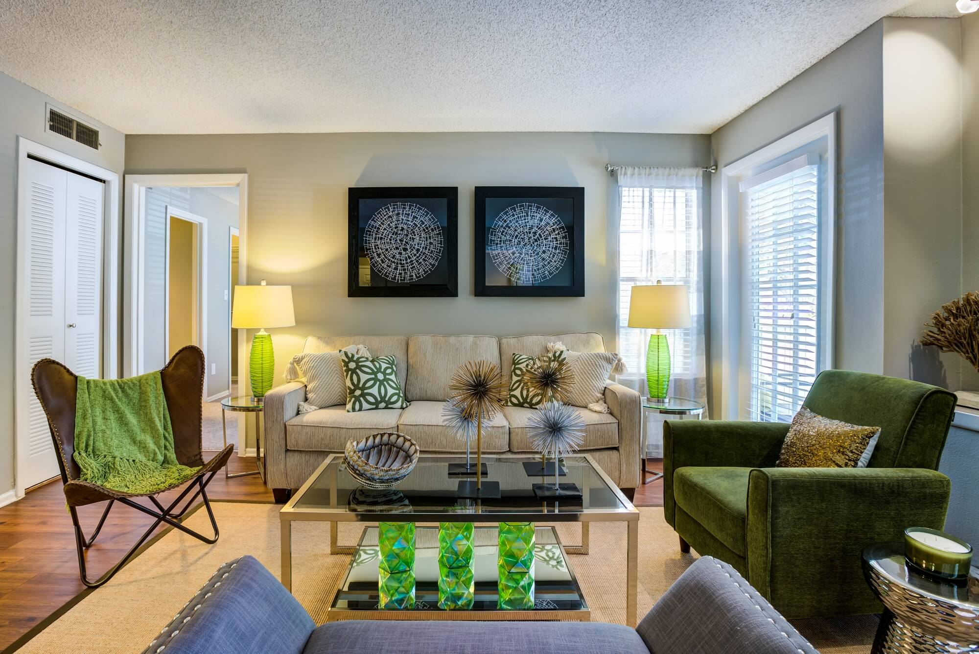 living area with wood floors, decor, and view of windows to patio.