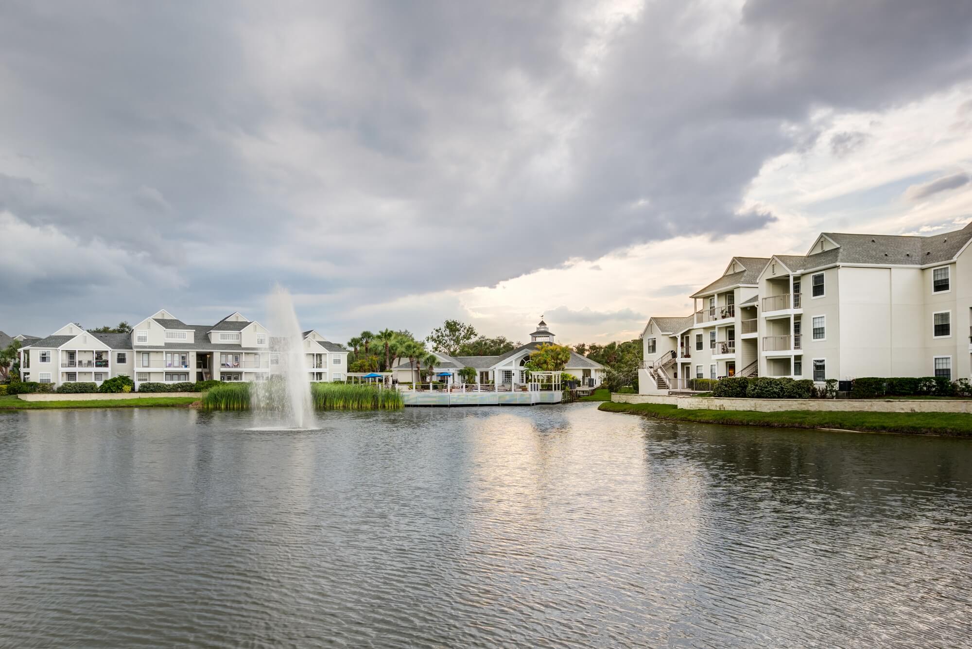 evening view of the lake with fountain and property buildings in the background.